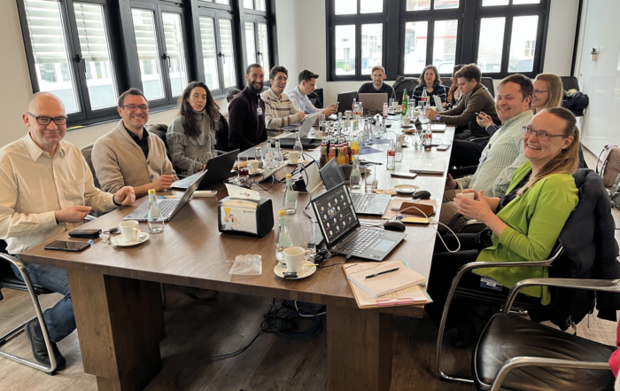 The NoVOC team members seated around a meeting table smiling